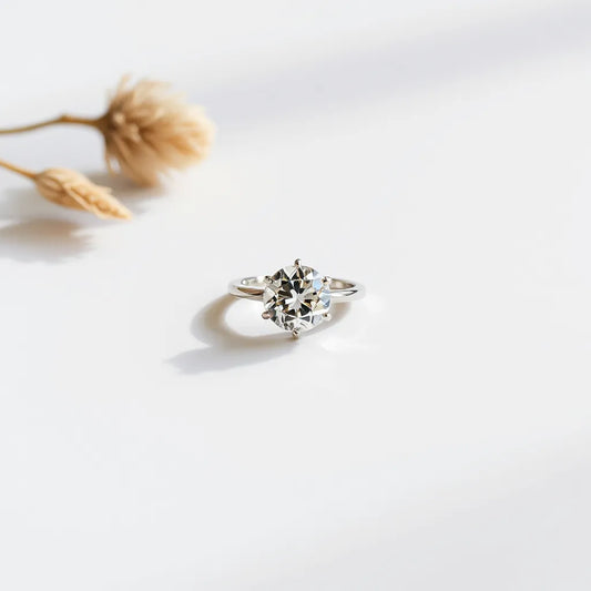An engagement-style ring with a clear faceted gemstone on a neutral background under soft natural light