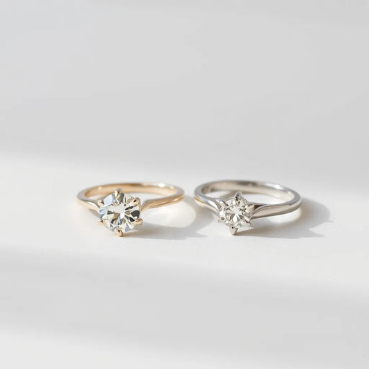 Two solitaire moissanite diamond rings with round stones on a neutral studio background